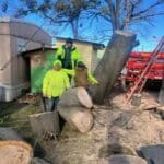 A few man standing next to tree being removed
