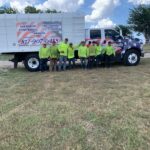 A Matt Tree Service crew member in yellow shirts standing in front of white work truck